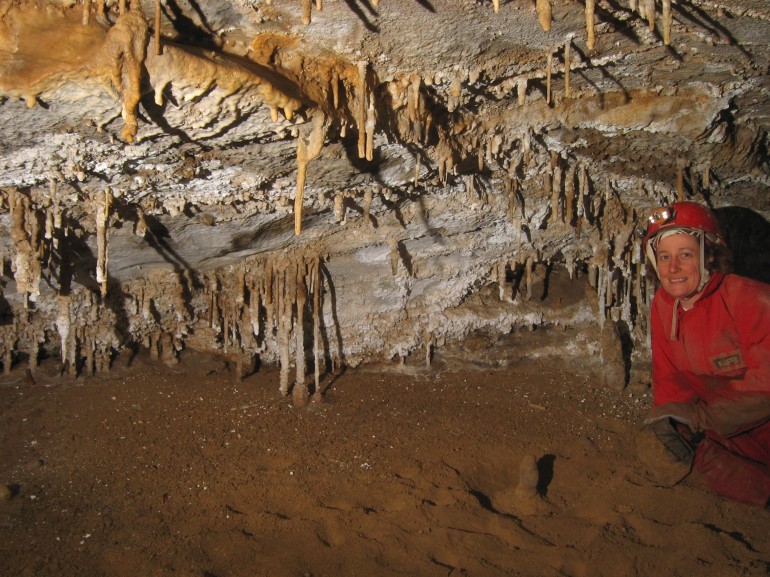 Leeanne near a lot of stalactites and white gypsum crust on the walls.
